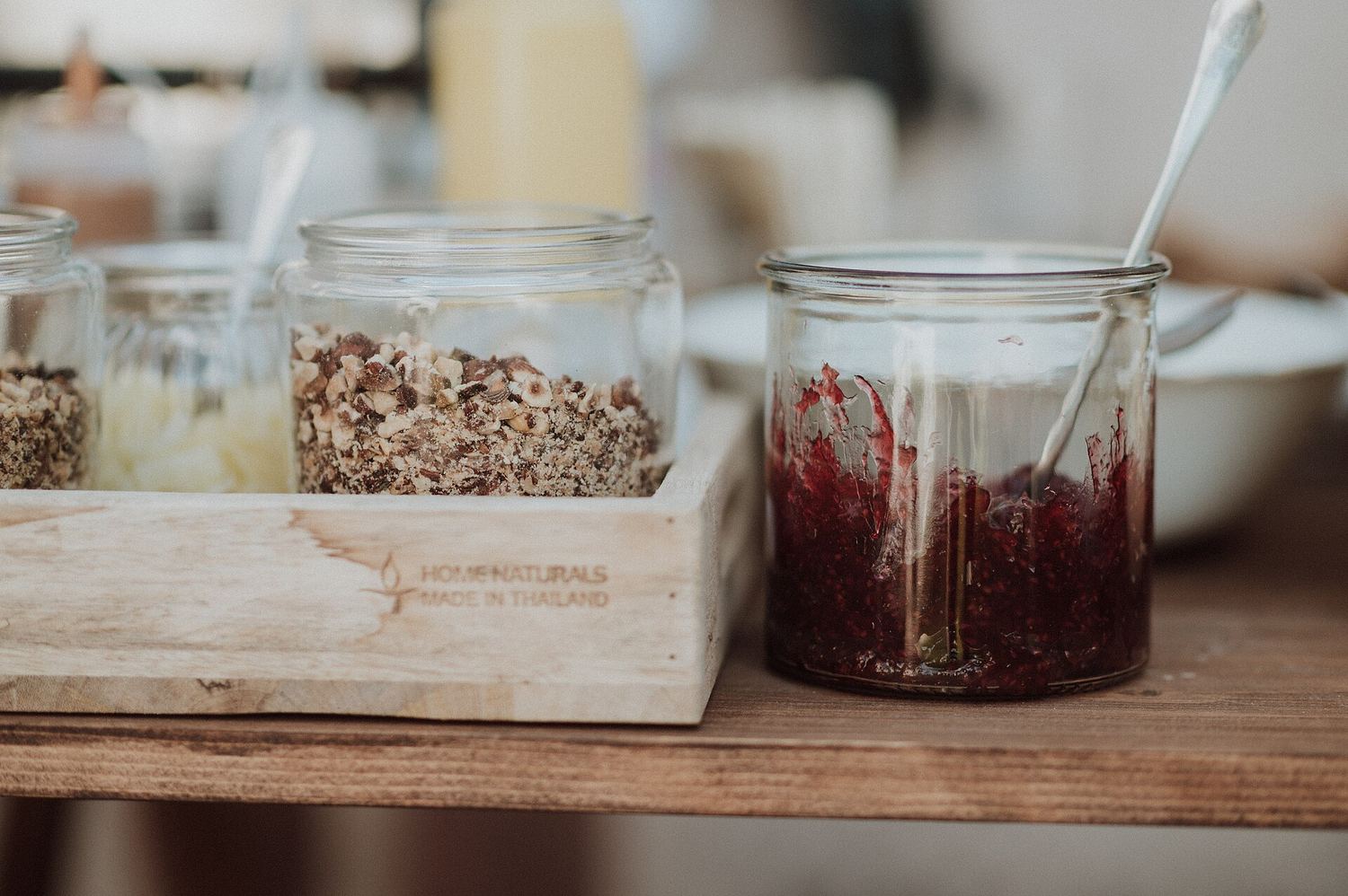 Jars of house granola and jam on a board